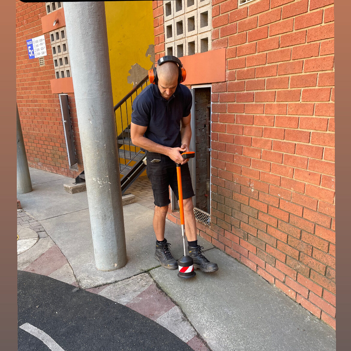 A technician doing a acoustic leak detection test with a ground microphone.