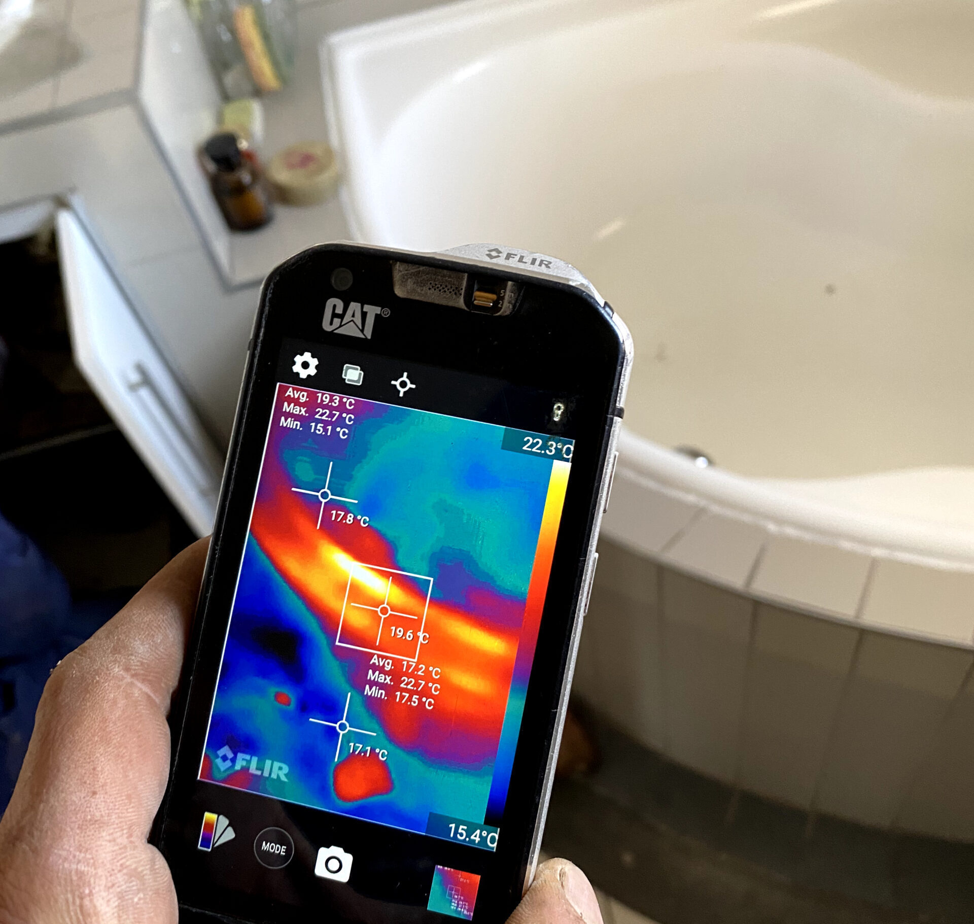 A thermal camera being used to inspect the outside of a bath for a water leak.
