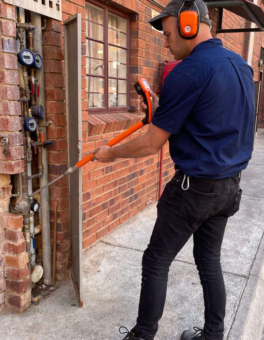 An acousic leak detection test being done at a building complex by a technician.